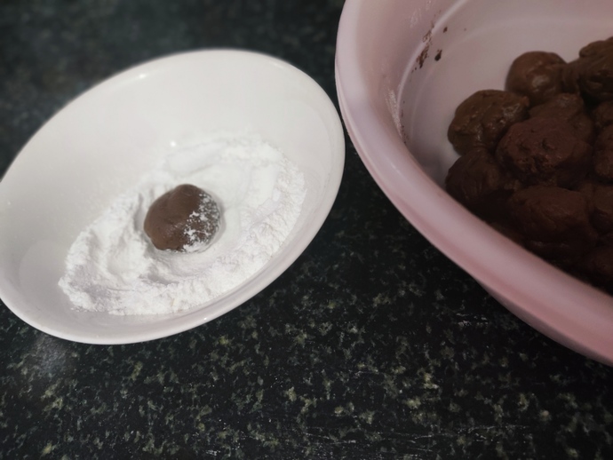 Hamurdan bir parça koparıp elinizle yuvarlayın ve pudra şekerine bulayıp yağlı kağıt serili tepsiye dizin.