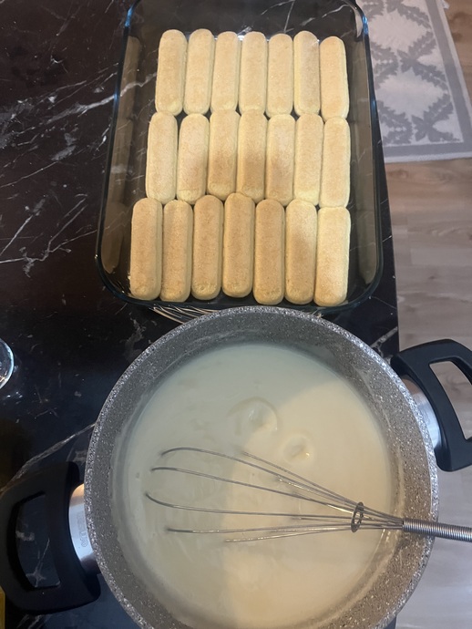 Kedi dillerini süte batırıp borcama dizince pastacı kremasını hazırlıyorum sıcakken hemen kedi dillerinin üzerine döküyorum .🤗