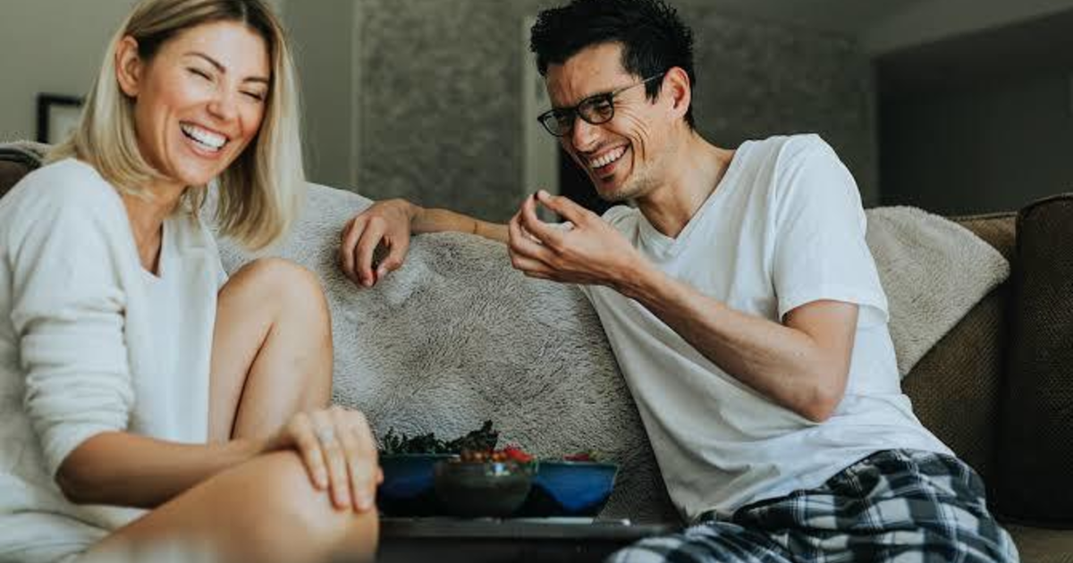 Проживание в семье. Супруги за столом. Мужчина представляет свою женщину с другим. Жена за столом. Мужчина и женщина смеются.